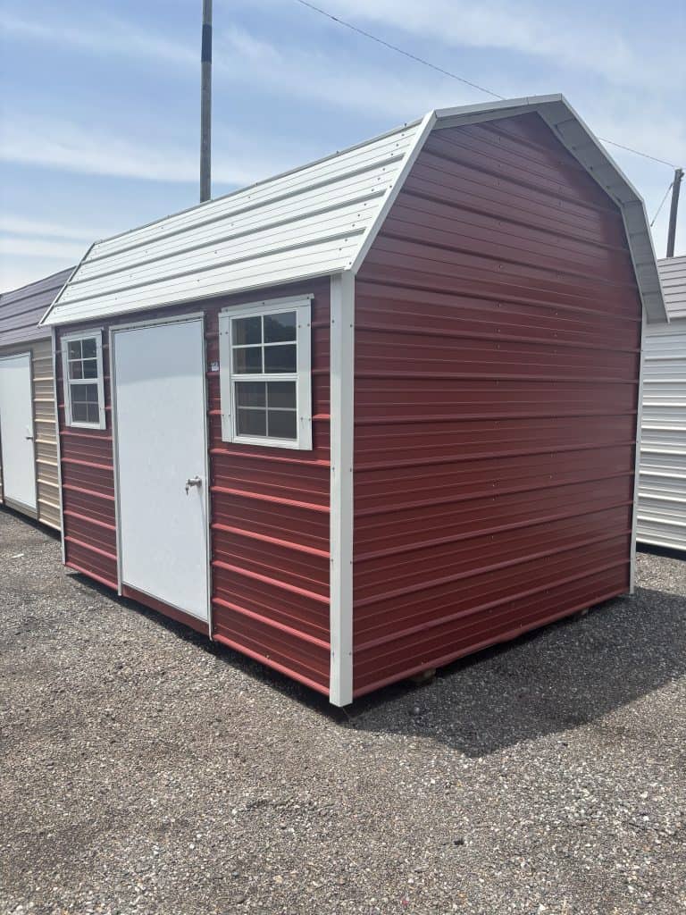 Red metal storage shed with white trim and double windows, used for durable outdoor storage solutions.