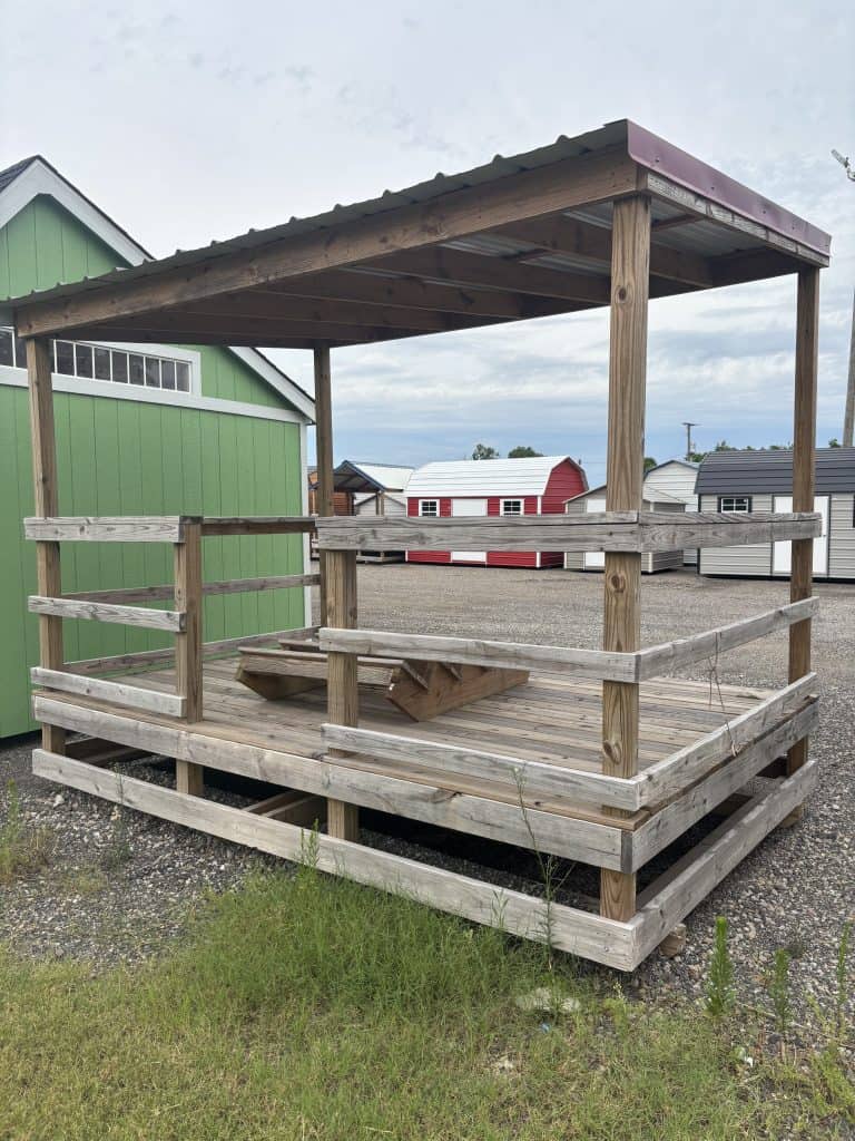 Heavy-duty wooden outdoor pavilion with a sloped metal roof, providing shade and seating for recreational or commercial use, ideal for commercial buildings or outdoor spaces.